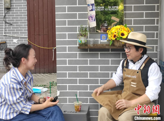 图为4月10日，吴家成与妻子在咖啡店外聊天。 中新社记者 邓霞 摄