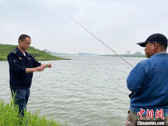 “劝渔”志愿者在河堤巡逻。　宋梅 摄