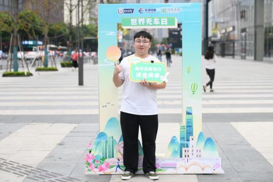 市民在“低碳出行绿色换乘”的宣传牌前打卡拍照。