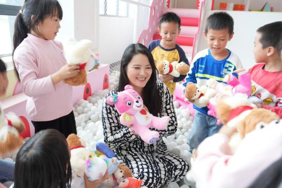 梁毓敏和孩子��一起玩玩具。�钊A峰 �z